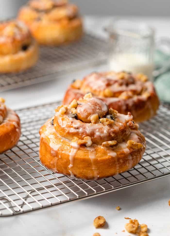 This easy Cinnamon Rolls recipe is from my grandmother, and is the best part about Thanksgiving and Christmas! A perfect holiday breakfast idea for the family. #brunch #sweetrolls #rolls #holidaybrunch #holidaybreakfastideas #makeaheadbreakfastideas Homemade Cinnamon Rolls on a wire rack drizzled with icing