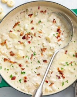 Clam Chowder in a soup pot with a spoon on the side and chopped bacon on top.