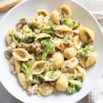 Creamy Sausage and Broccoli Pasta in a white bowl with red pepper flakes on top.