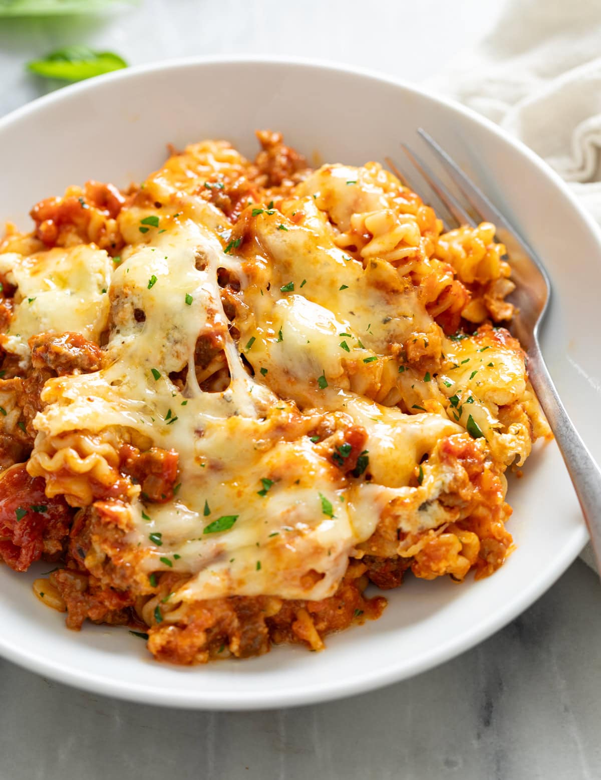 A side view of Lazy Lasagna in a white bowl with a fork on the side.